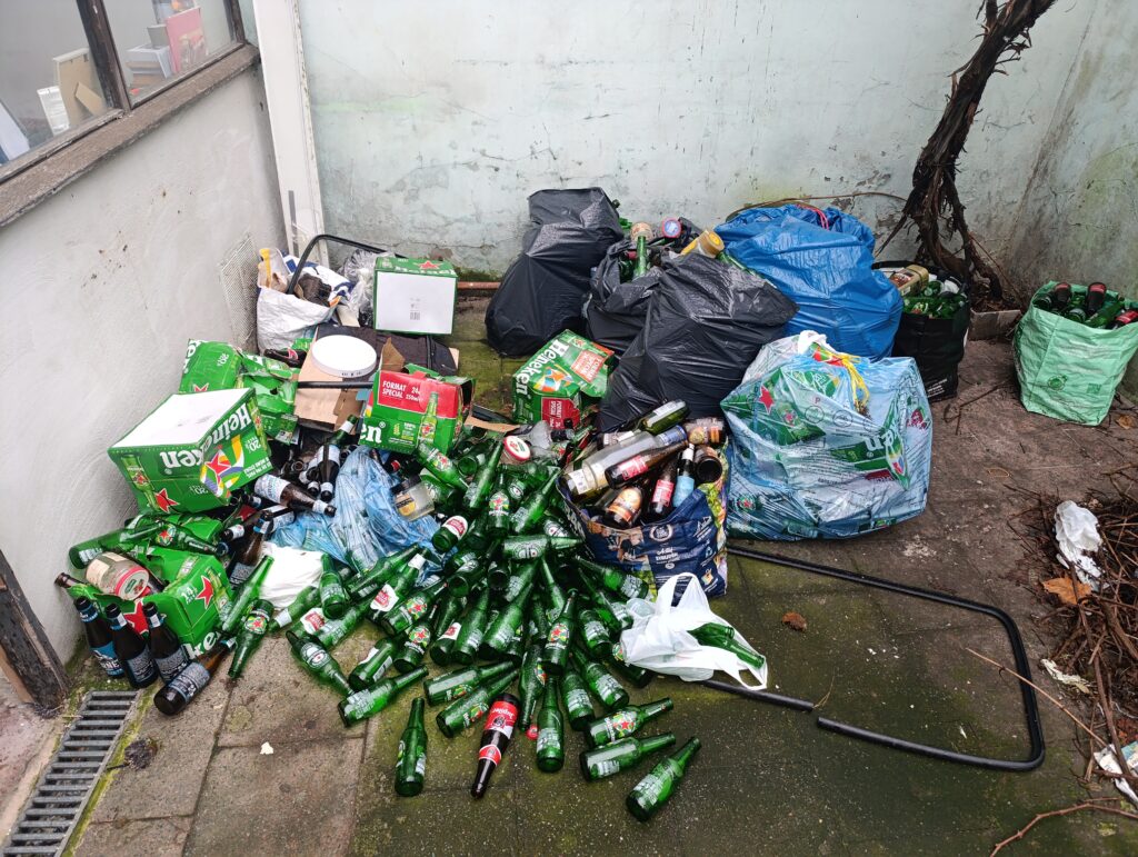 Déchets attirant les souris dans une cour urbaine à Bruxelles Cour arrière encombrée à Bruxelles avec canettes, bouteilles et sacs poubelle, terrain propice aux infestations de souris.
